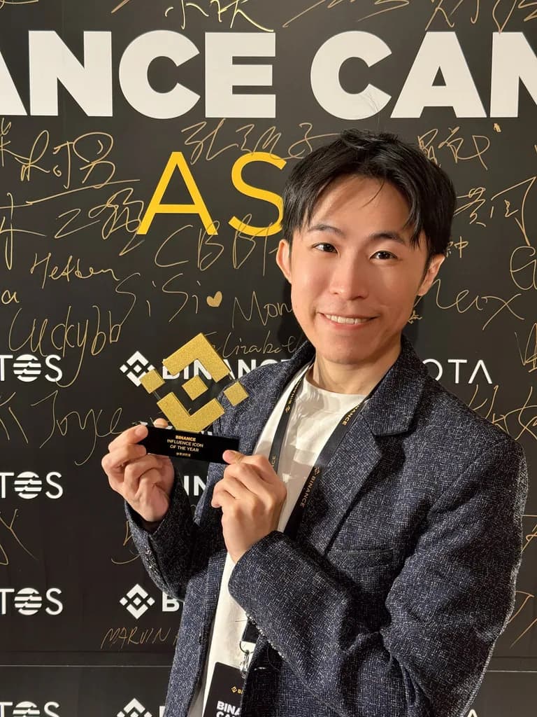 氣球柯男手持幣安年度影響力達人獎獎座,站在 Binance Campus Asia 簽名牆前